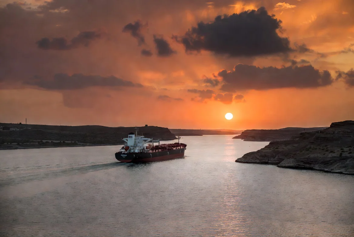 Petrolero en el Estrecho de Ormuz bajo cielo dramático al atardecer, simbolizando tensiones geopolíticas actuales entre